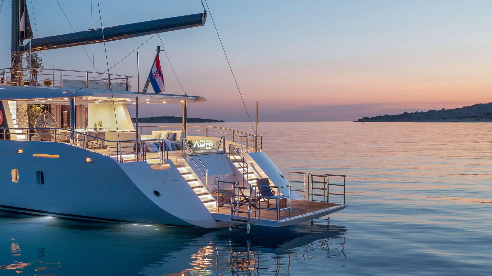 luxury yacht stern deck with swimming platform and stairs at sunset anchorage