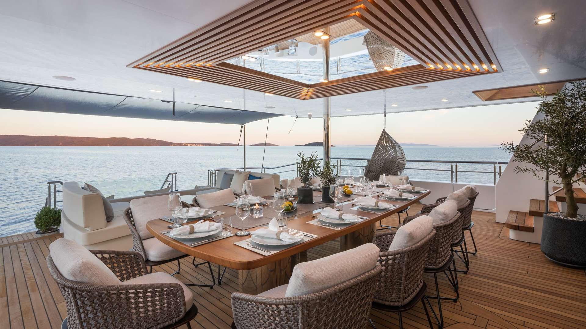 yacht aft deck dining table with place settings under retractable roof at sunset