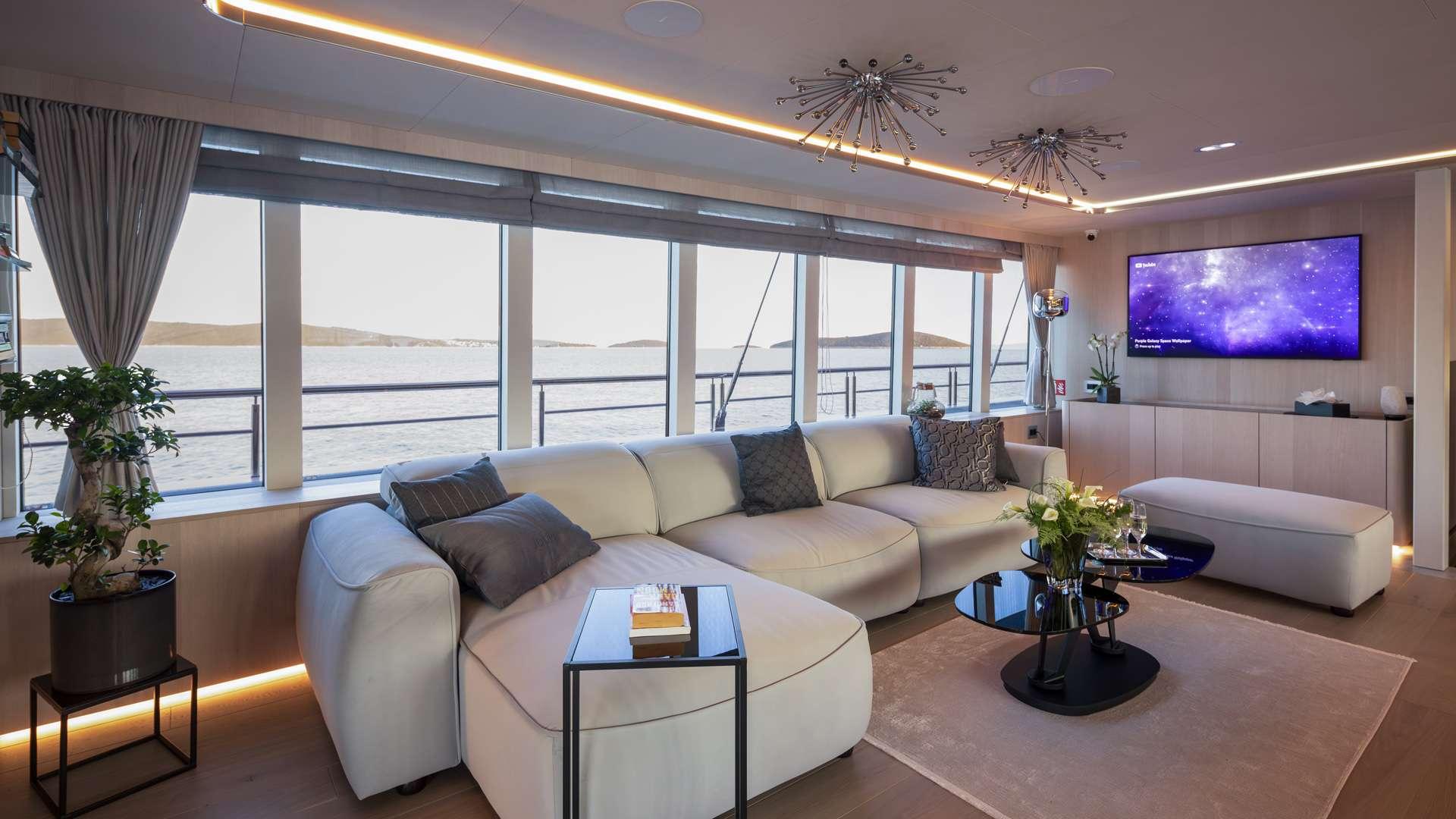 yacht cinema room featuring large wall-mounted screen and cream sectional sofa with panoramic windows