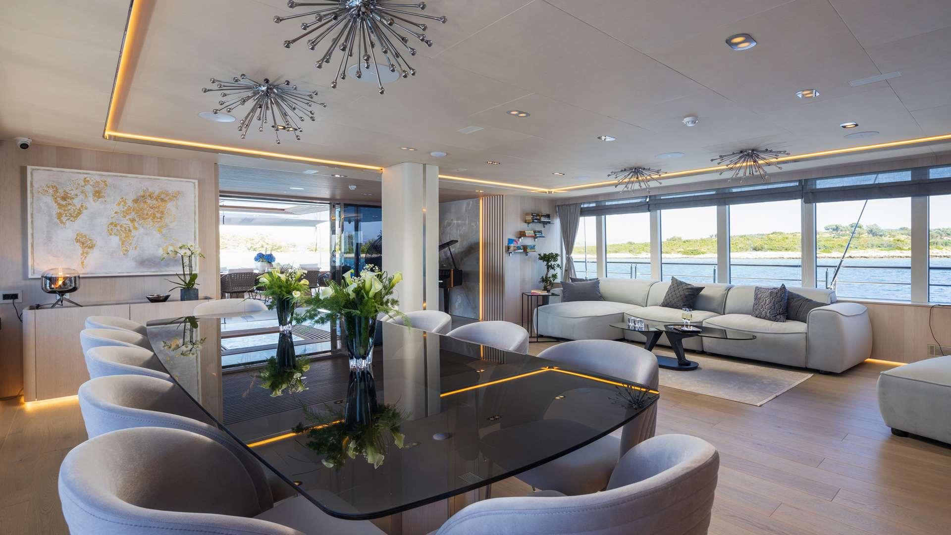 luxury yacht main salon with modern seating, dining table, and panoramic coastal views