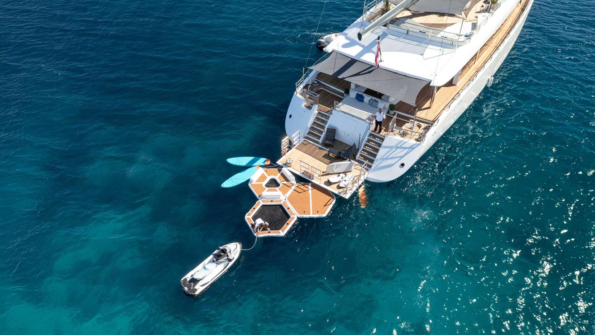 luxury yacht with deployed hexagonal floating water platform and tender boat in turquoise waters