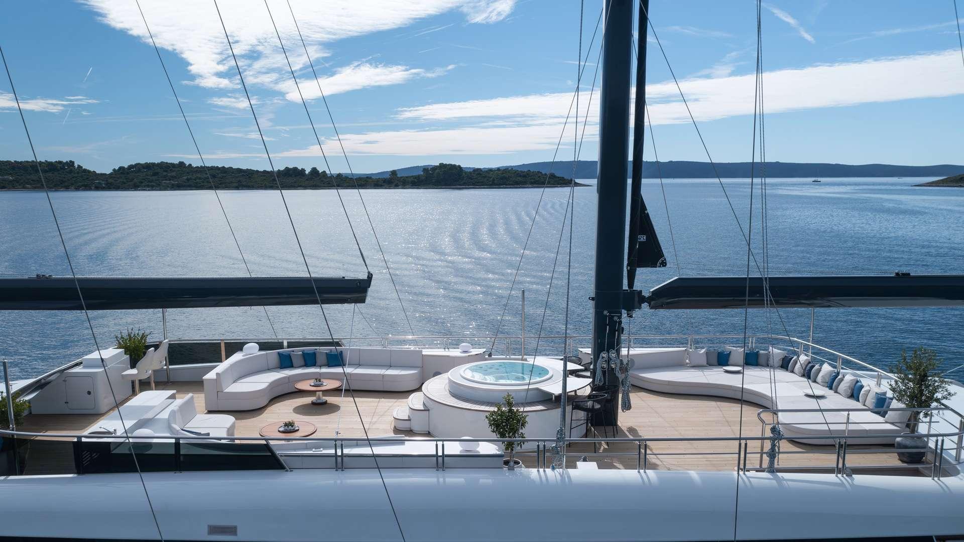 yacht deck jacuzzi surrounded by white cushioned seating and dining areas