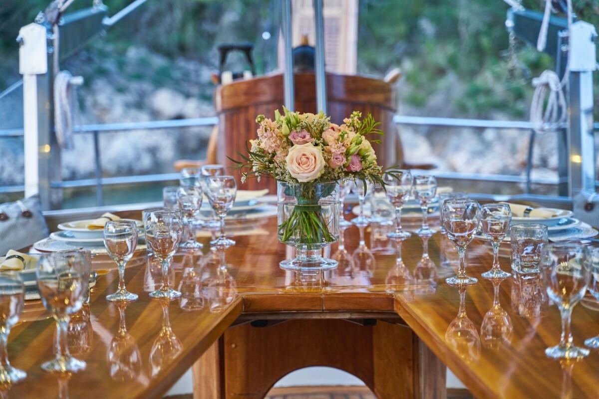 Crystal glassware and floral centerpiece on polished wooden yacht dining table