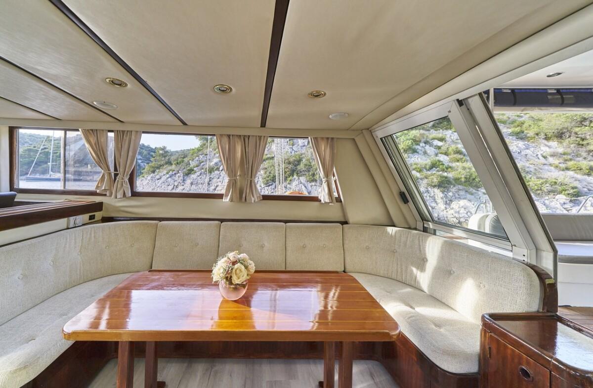 yacht salon interior with cream banquette seating around wooden dining table