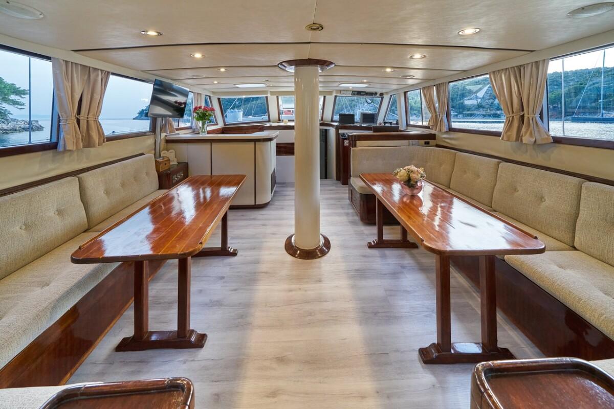 yacht main salon interior with wood dining tables and panoramic windows