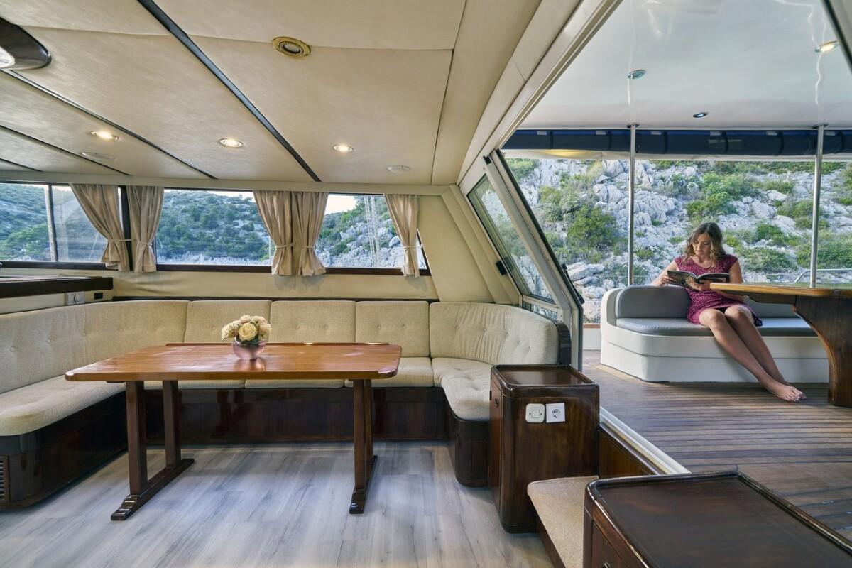 luxury yacht salon with U-shaped seating, dining table and panoramic coastal views
