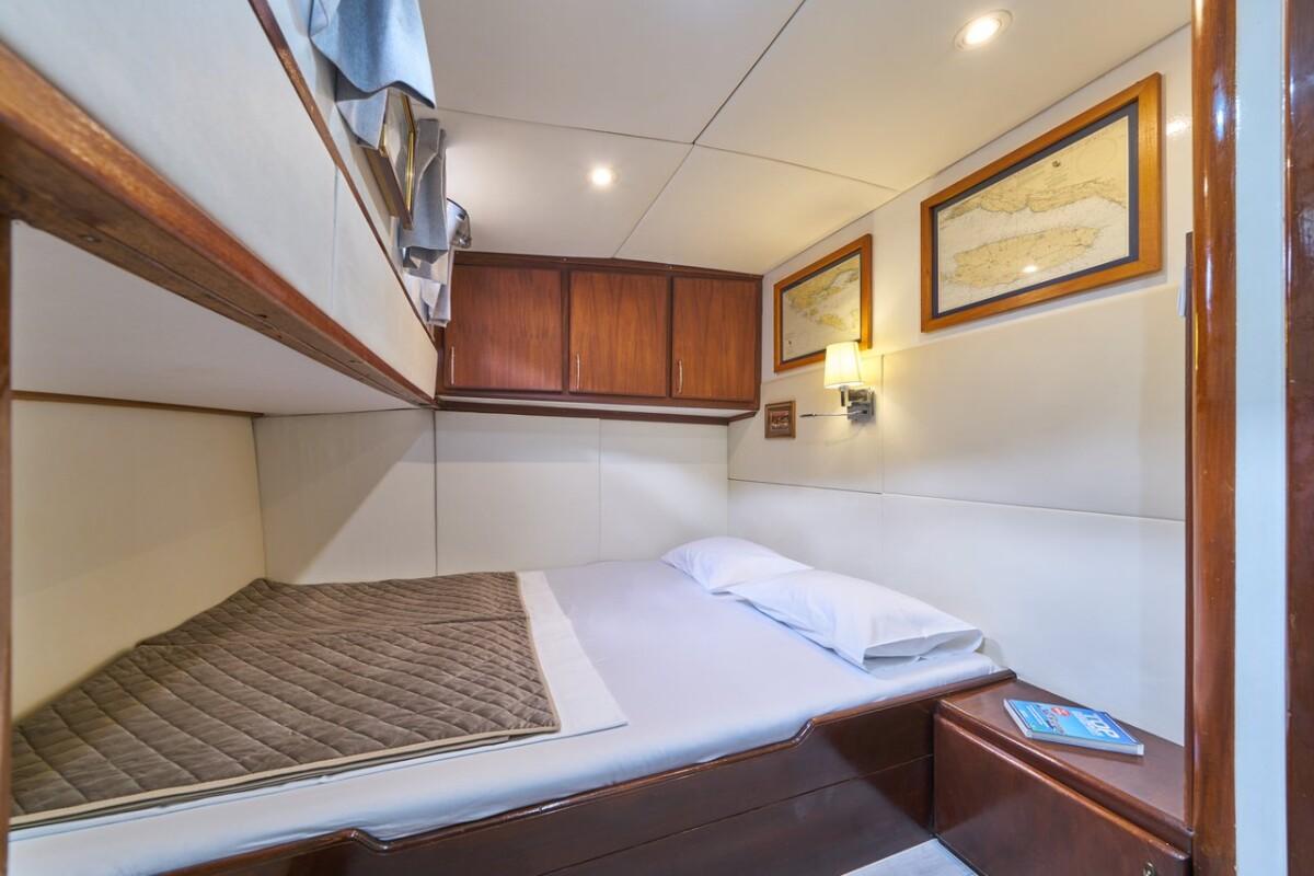 yacht cabin interior with white bedding and wood paneling