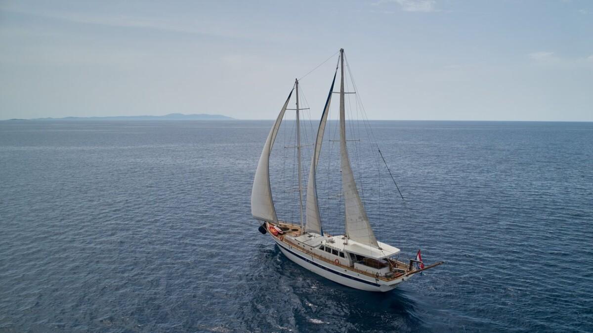 Aerial view of wooden gulet yacht sailing with white sails on blue water