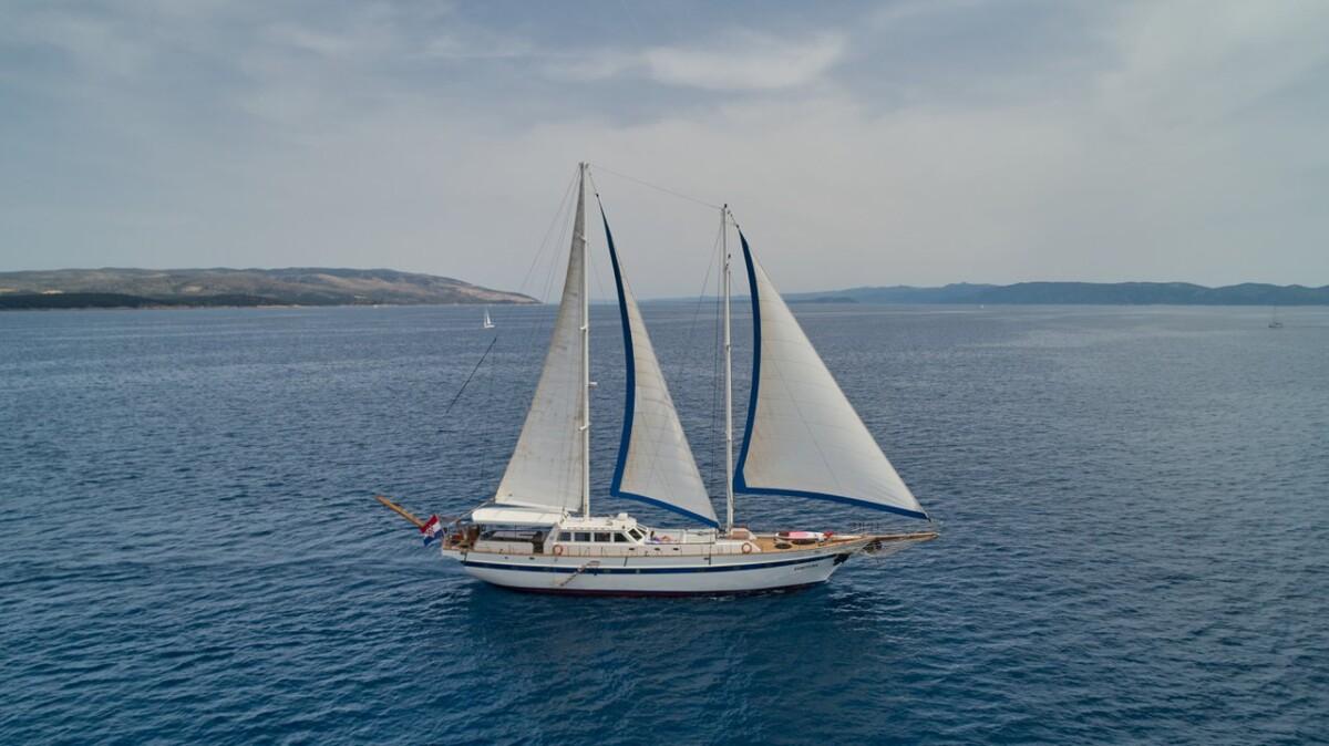 Traditional sailing yacht with white sails cruising on calm blue Mediterranean waters