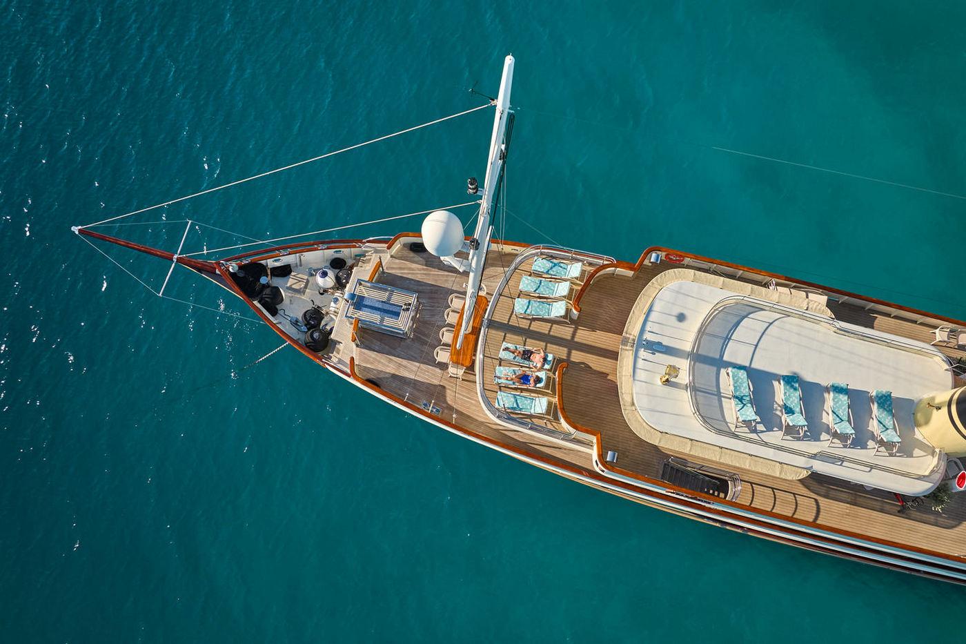 Aerial view of white sailing yacht with teak decking on turquoise water
