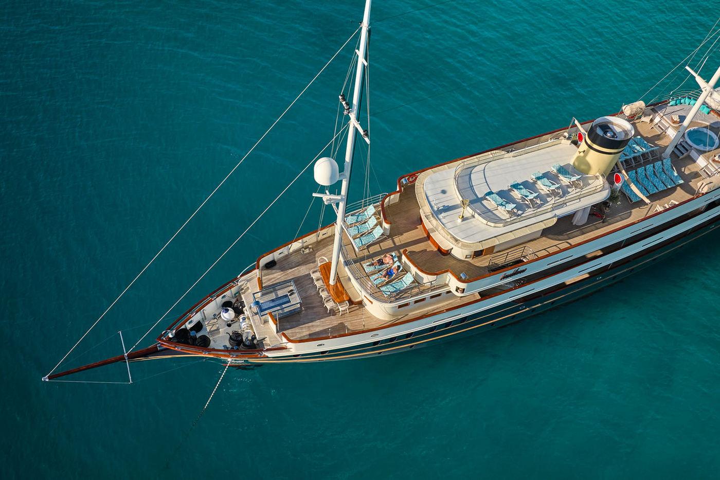 Aerial view of white luxury gulet yacht anchored in crystal clear turquoise water