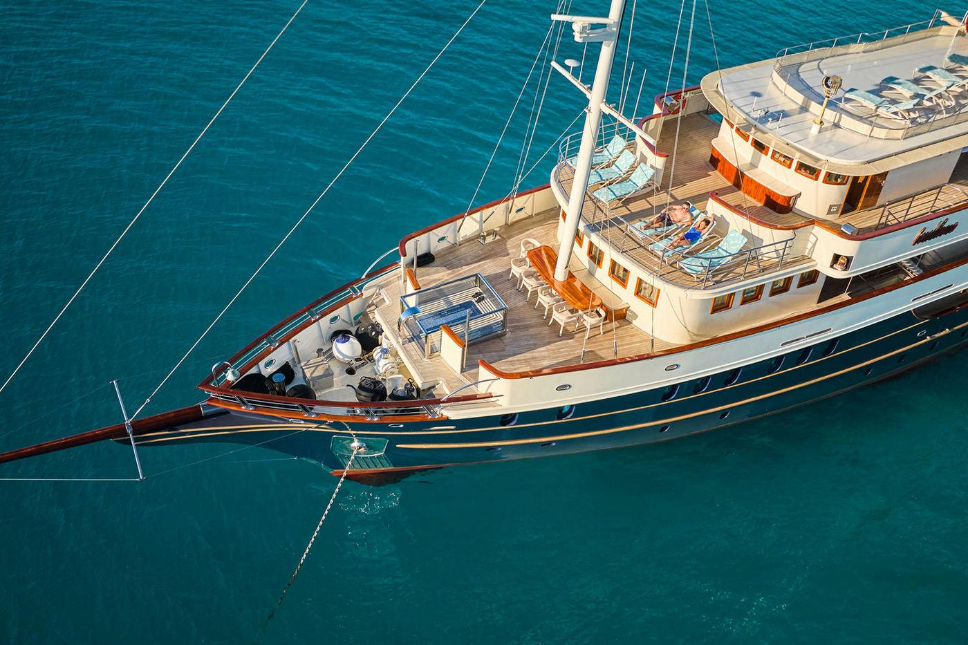Aerial view of classic wooden gulet yacht with orange trim anchored in clear blue waters