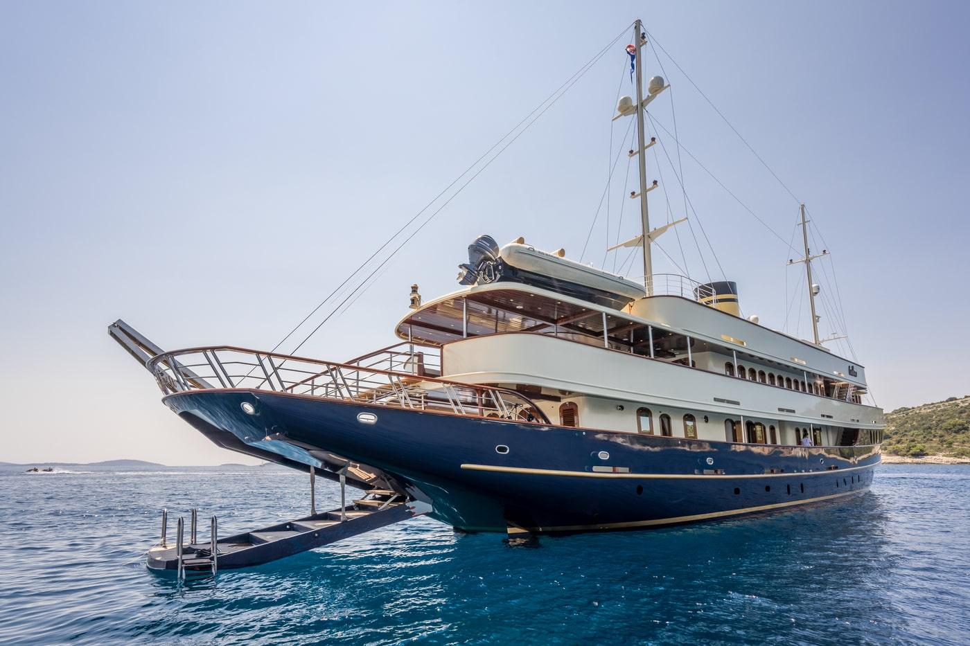 Classic wooden gulet yacht with navy blue hull anchored in turquoise waters