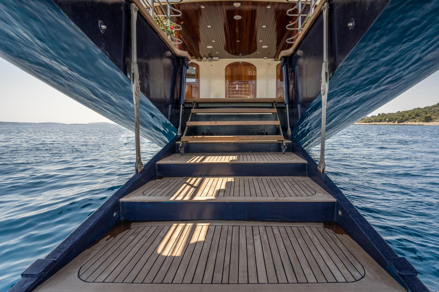 Luxury yacht stern swim platform with multiple teak levels and blue water