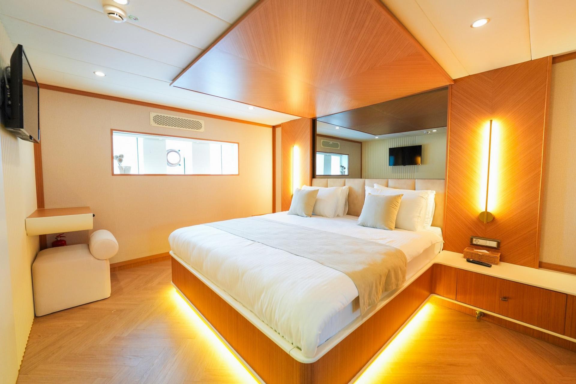 yacht cabin interior with double bed, wood paneling, ambient LED lighting and ensuite bathroom