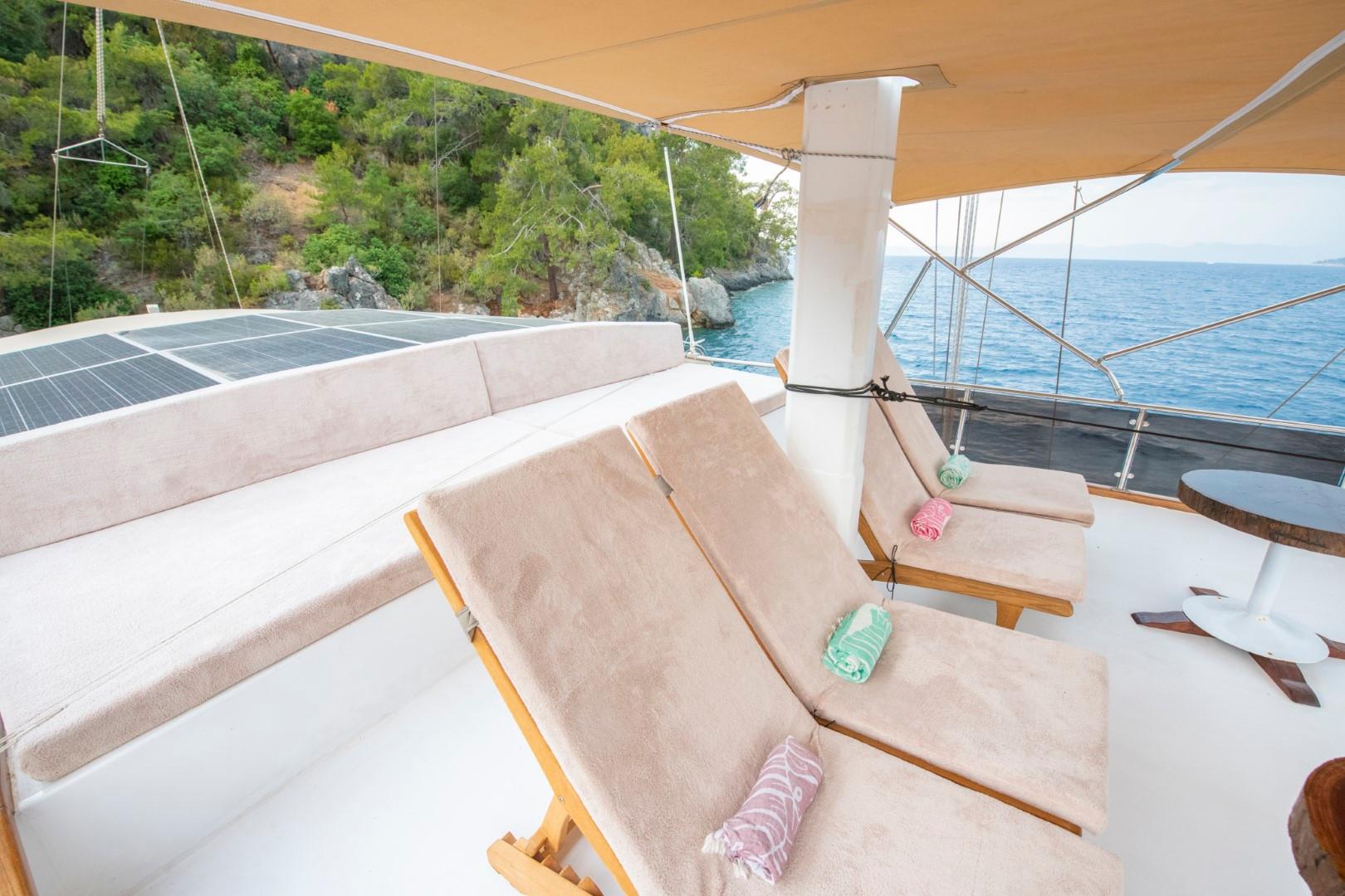 yacht sun deck with beige cushioned loungers, awning shade, and coastal bay view