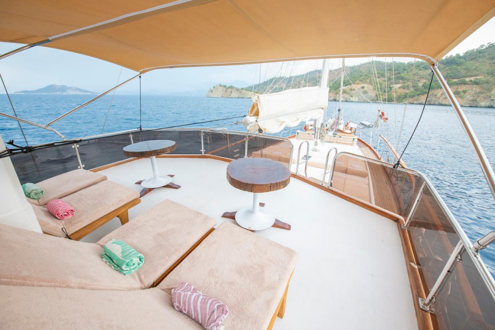 upper deck lounge with curved bench seating, round table and beige awning