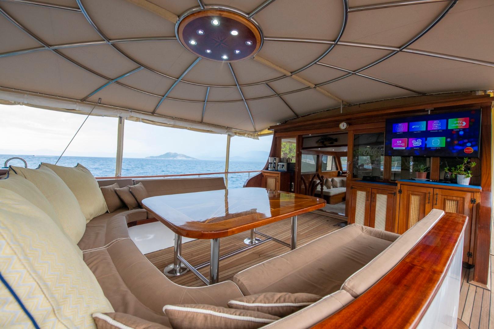 yacht salon with curved seating, dining table, entertainment center and sea views