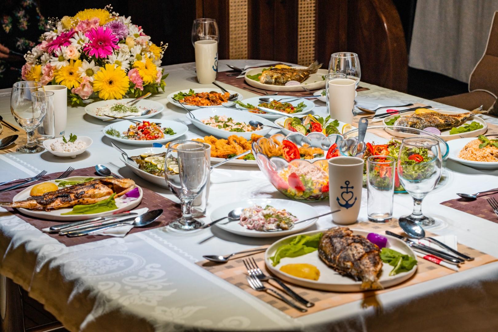 yacht dining table with grilled fish, salads, and Mediterranean cuisine served on white plates