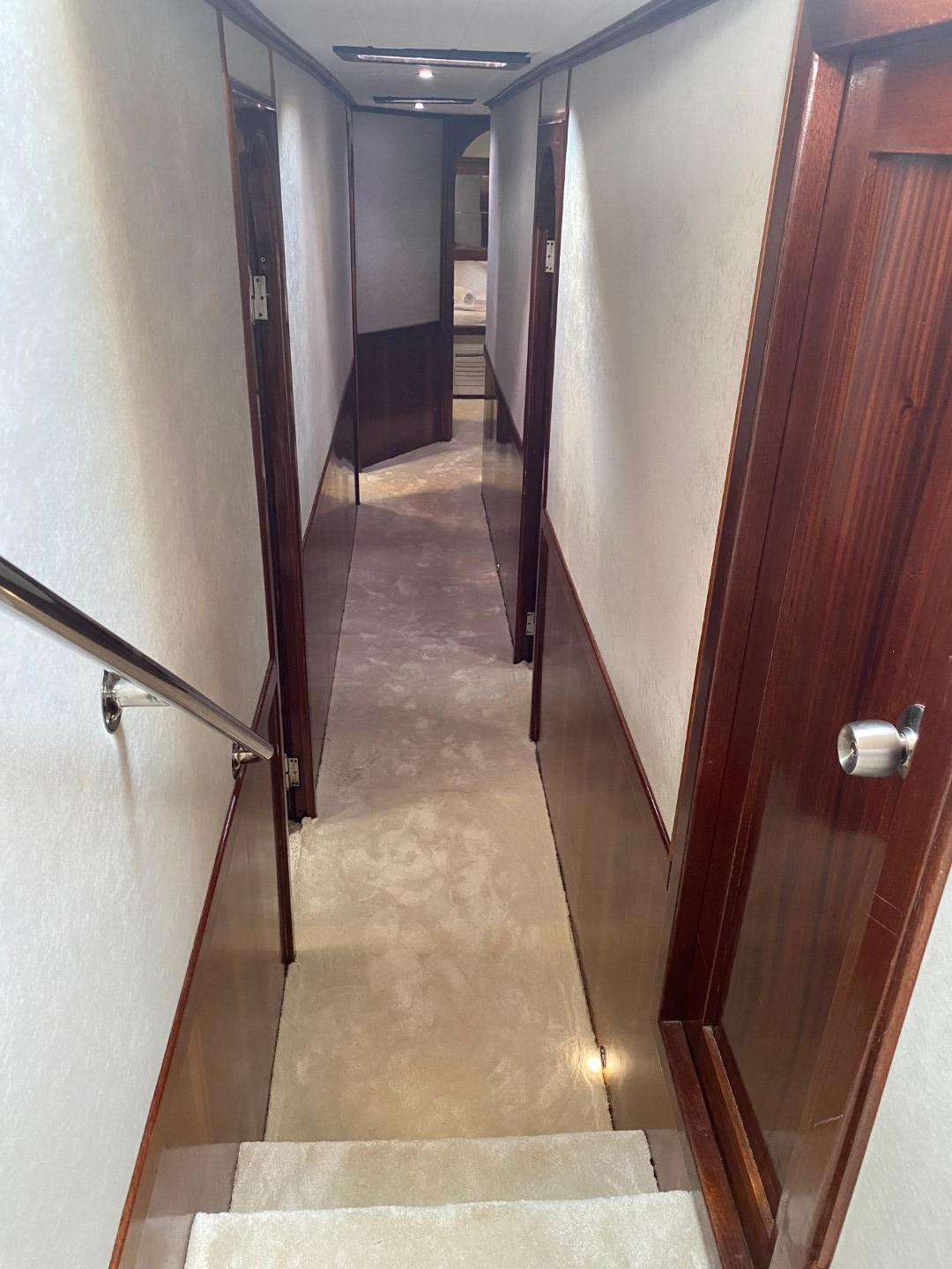 yacht interior corridor with wooden cabin doors, handrail and marble flooring