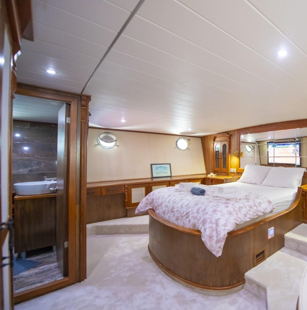 master cabin featuring king bed with curved headboard and en-suite bathroom entrance