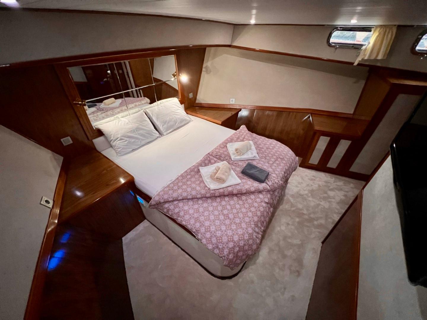 yacht cabin interior with double bed, mirrored headboard, portholes and wood paneling