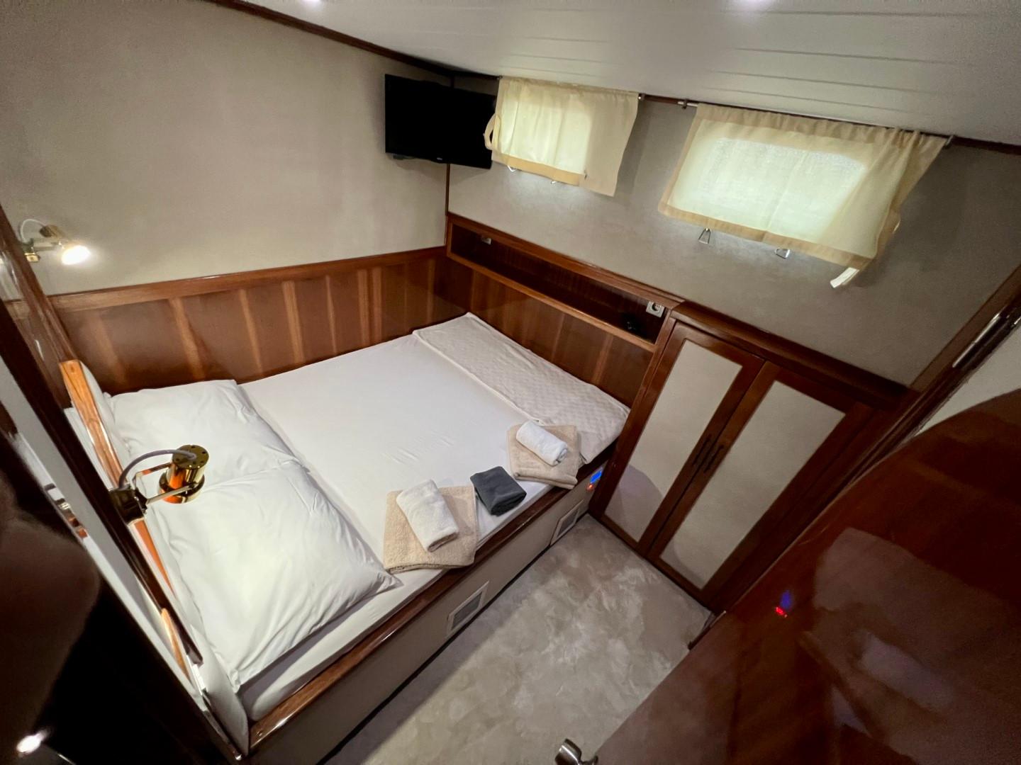 yacht guest cabin featuring double bed with white linens and rich wood paneling