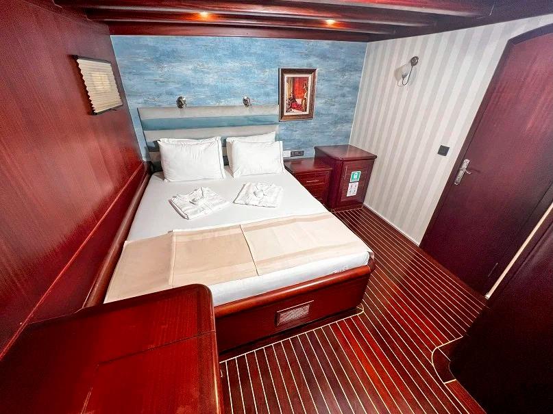 yacht guest cabin featuring double bed with white linens and rich mahogany woodwork
