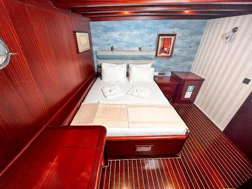 Guest cabin interior featuring double bed with white linens and red upholstered seating area