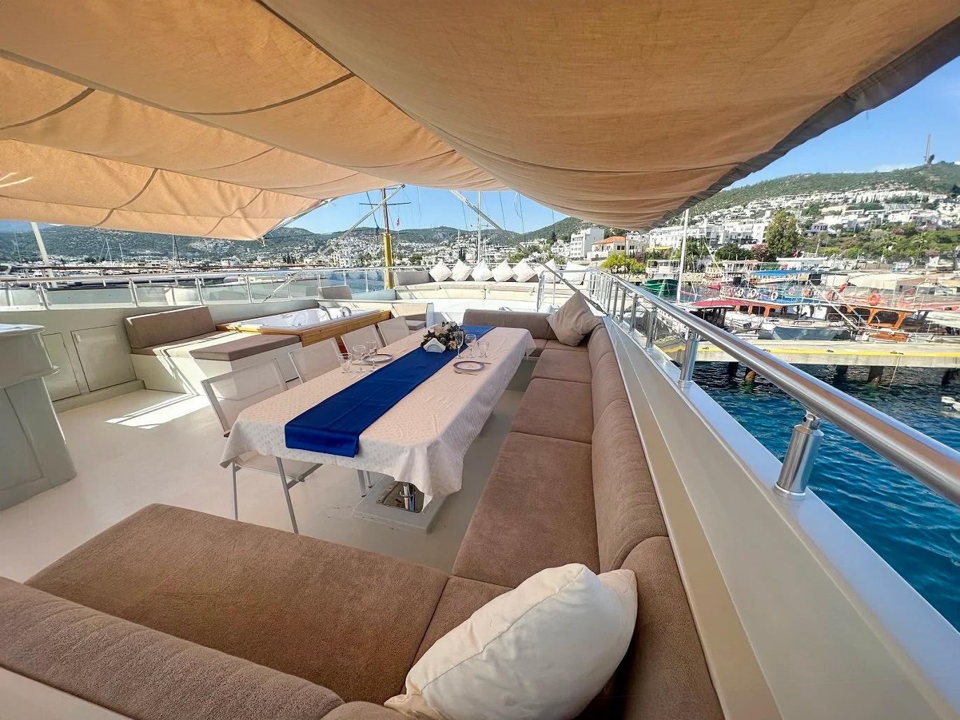 yacht upper deck lounge with massage table, built-in seating, and marina harbor view