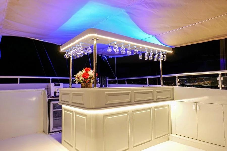 yacht outdoor bar with white cabinetry, hanging glassware rack and purple LED ceiling lighting
