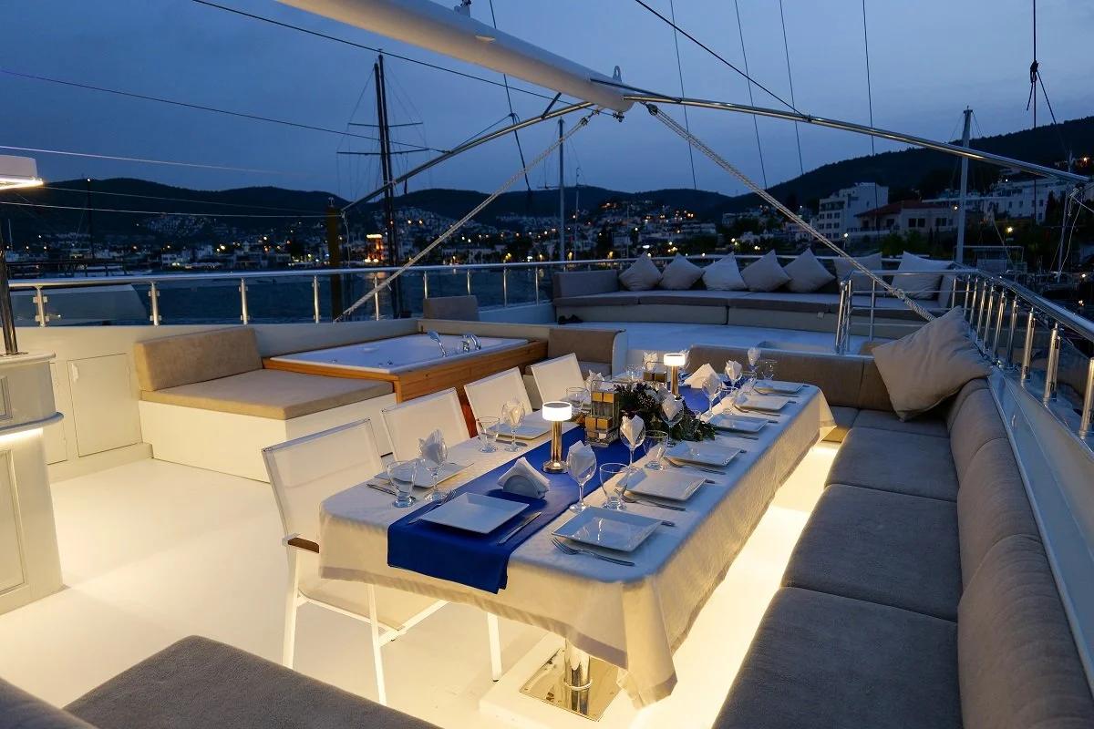 yacht upper deck dining area with formal white table setting and blue runner at twilight