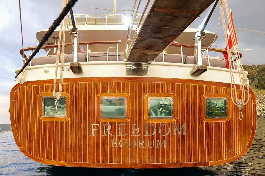 Freedom yacht stern showing teak planked hull with four portholes and Bodrum registration