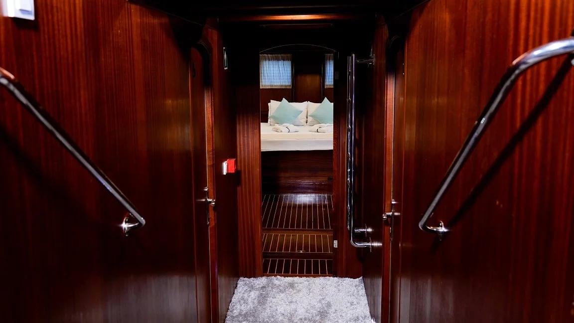 yacht interior wooden stairway with handrails leading down to guest cabin with visible bed