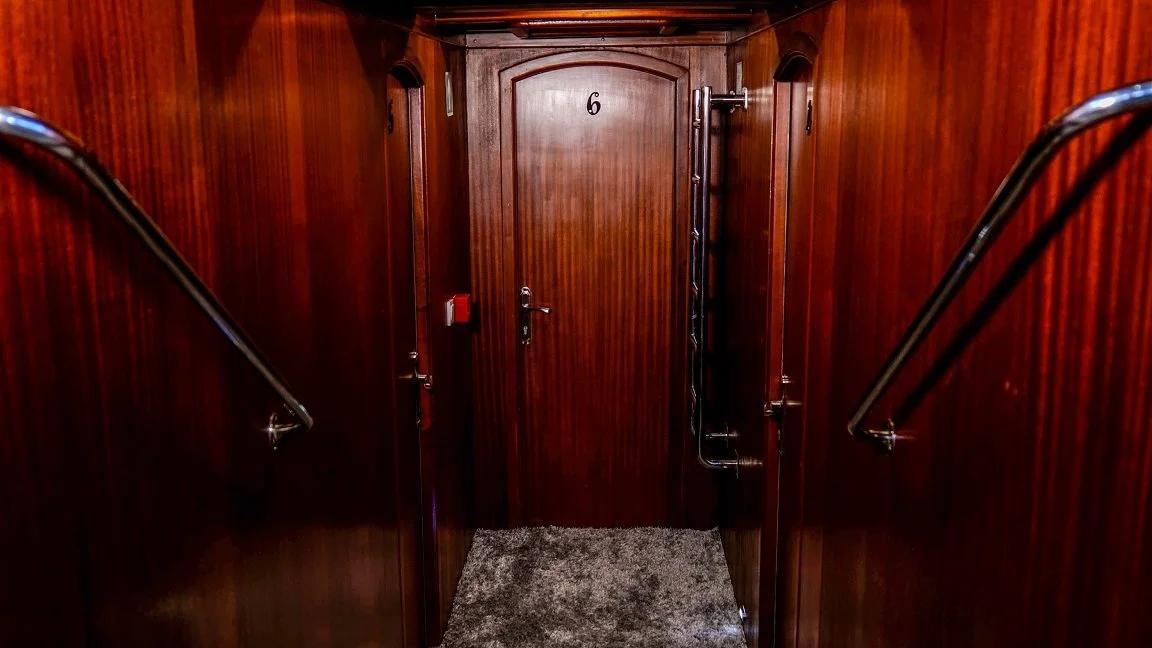 yacht guest cabin entrance door number 6 with polished wood paneling and handrails