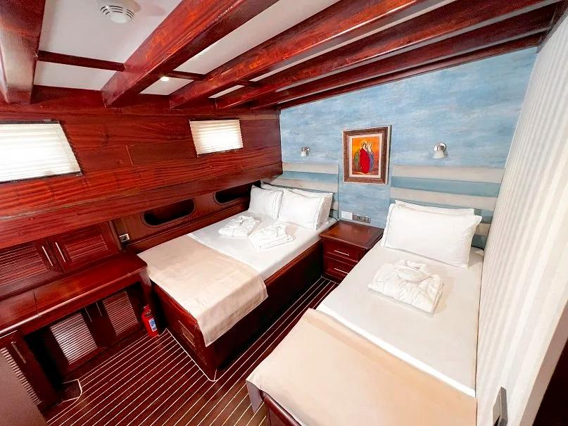 yacht twin cabin featuring two single beds with white linens and wooden beam ceiling