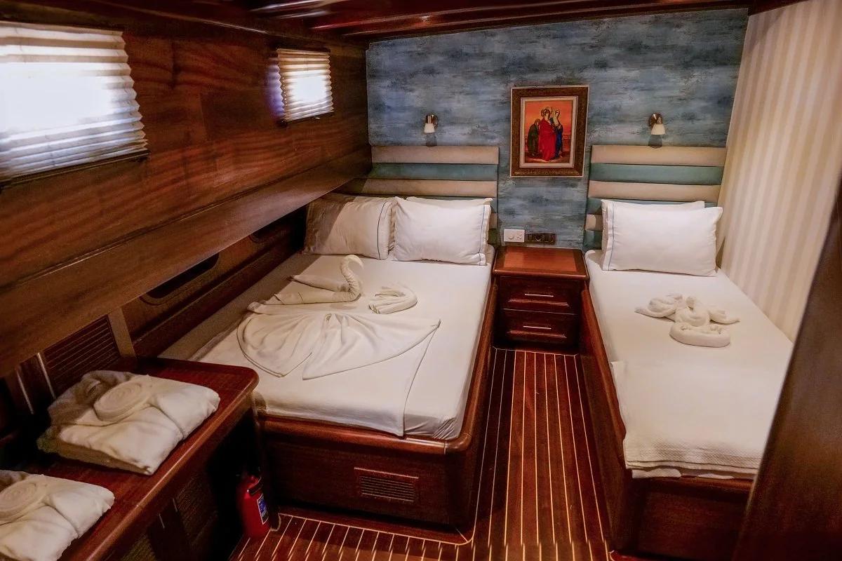 yacht twin cabin with two single beds, striped headboards, portholes and religious artwork