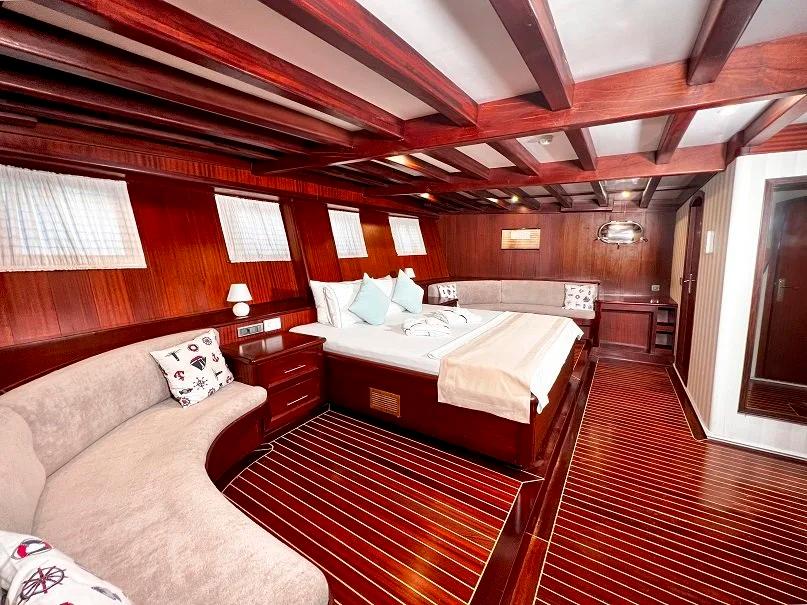 yacht cabin interior with double bed white linens curved seating area wood paneling