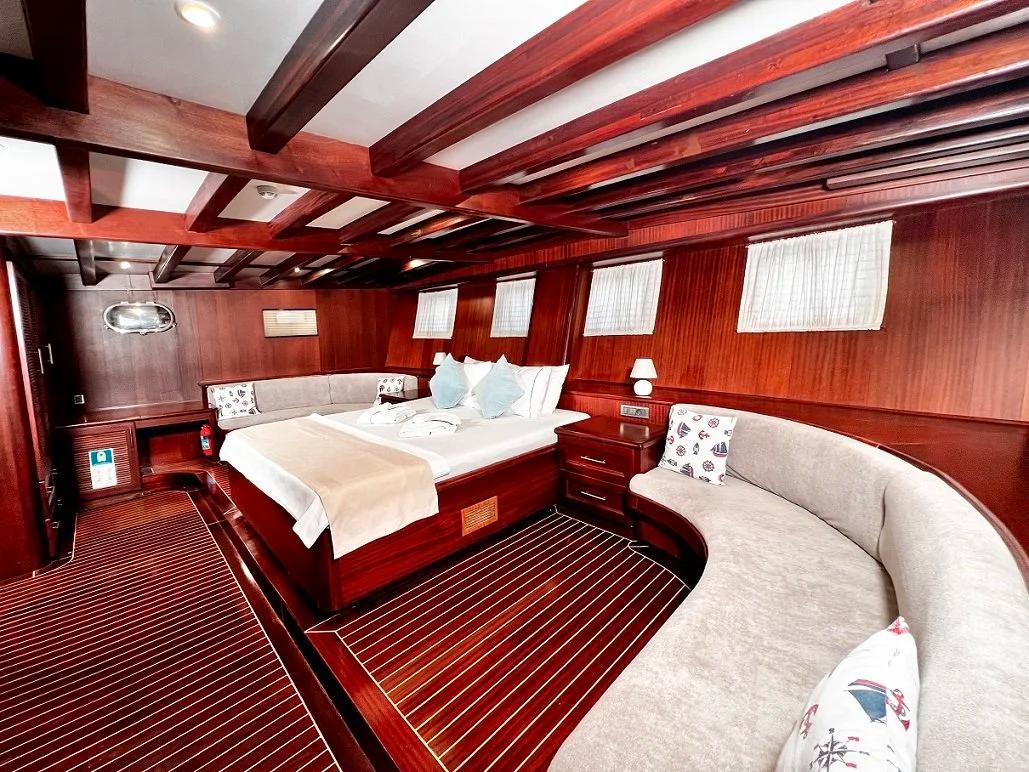 luxury yacht master cabin featuring double bed with white linens and curved upholstered seating area