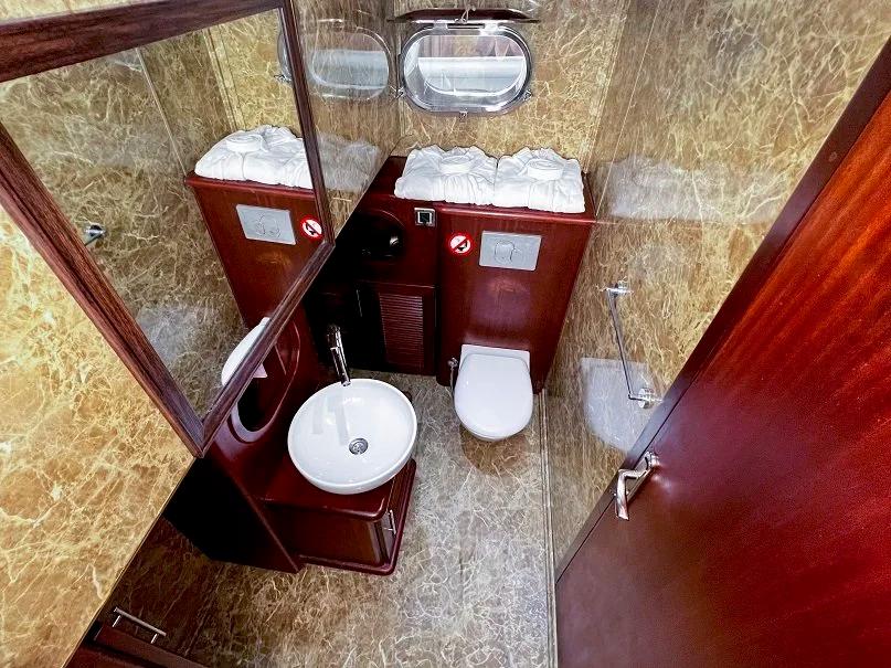 luxury yacht ensuite bathroom with white round sink, toilet, marble walls and mirror