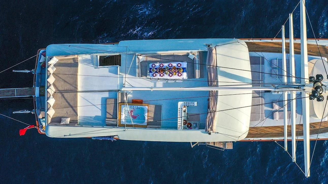 aerial drone shot of white luxury yacht with multiple deck levels and mast at anchor