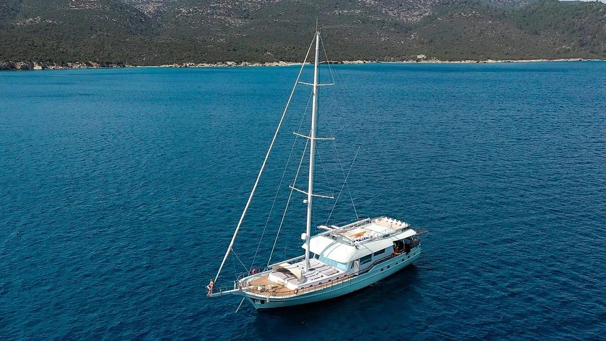 aerial view of white gulet yacht with single mast anchored in crystal blue Mediterranean waters