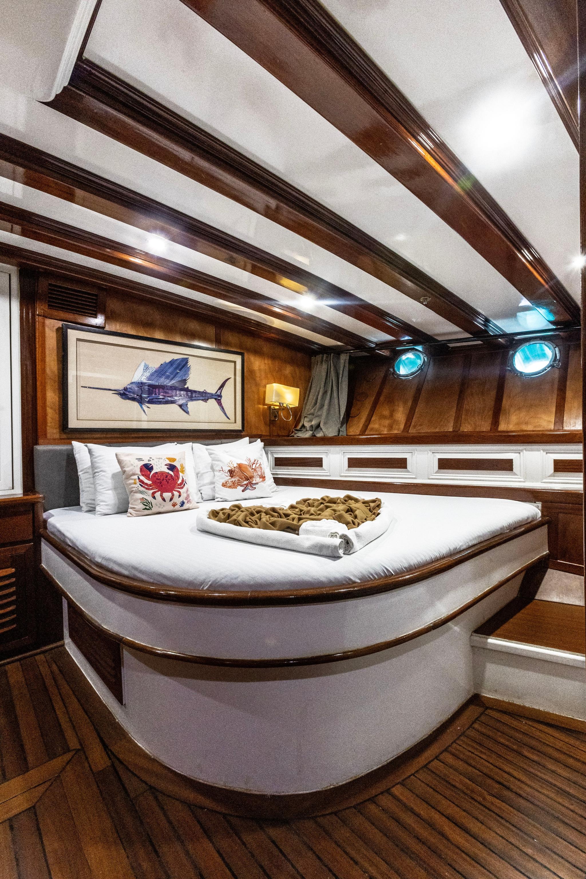 yacht guest cabin featuring curved white bed with decorative pillows and sailfish artwork