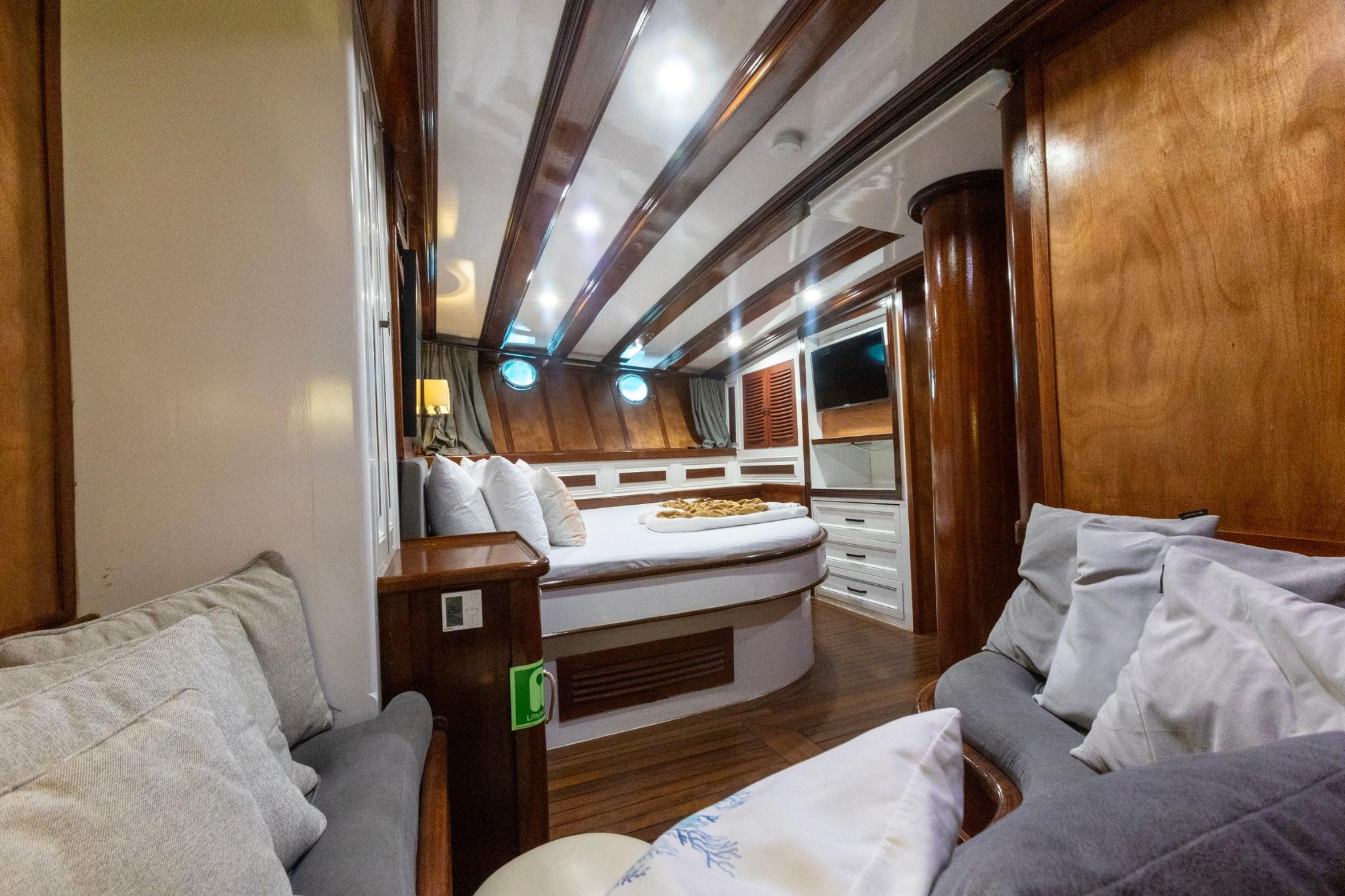 yacht cabin interior featuring round bed with white bedding and built-in seating