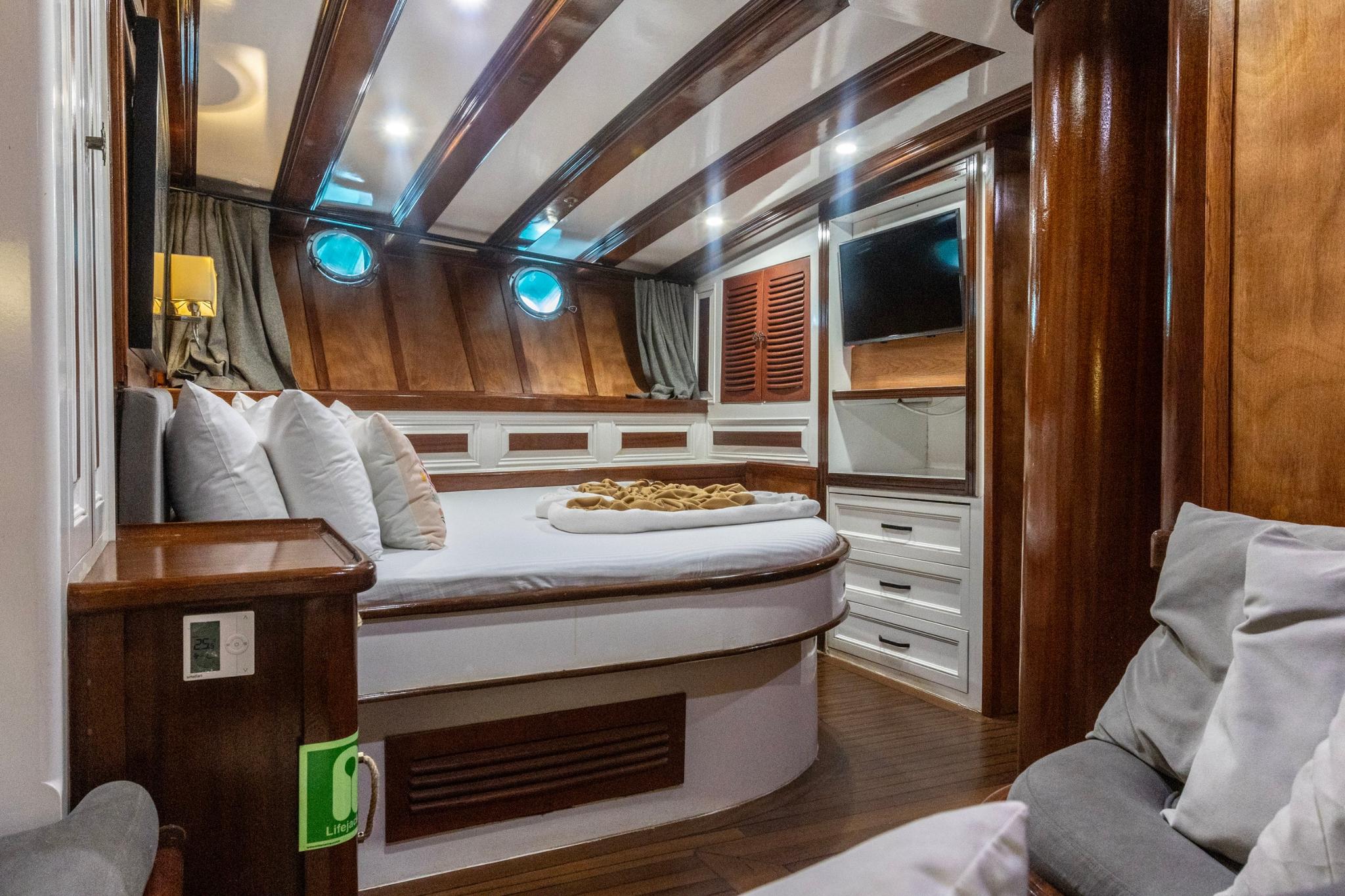 yacht guest cabin featuring curved bed with white linens and built-in storage drawers