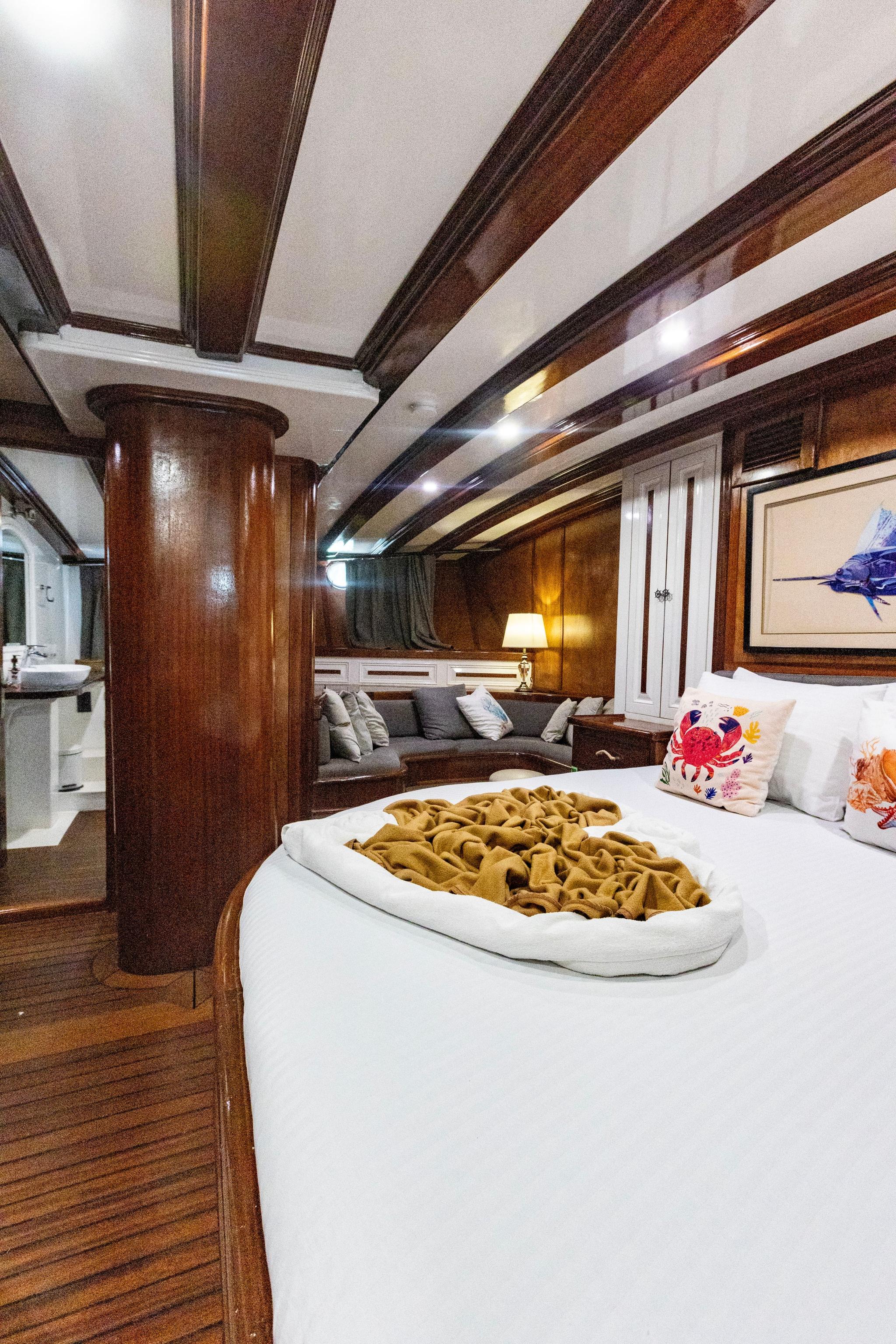 yacht cabin featuring round bed with mustard yellow throw and marine-themed decorative pillows