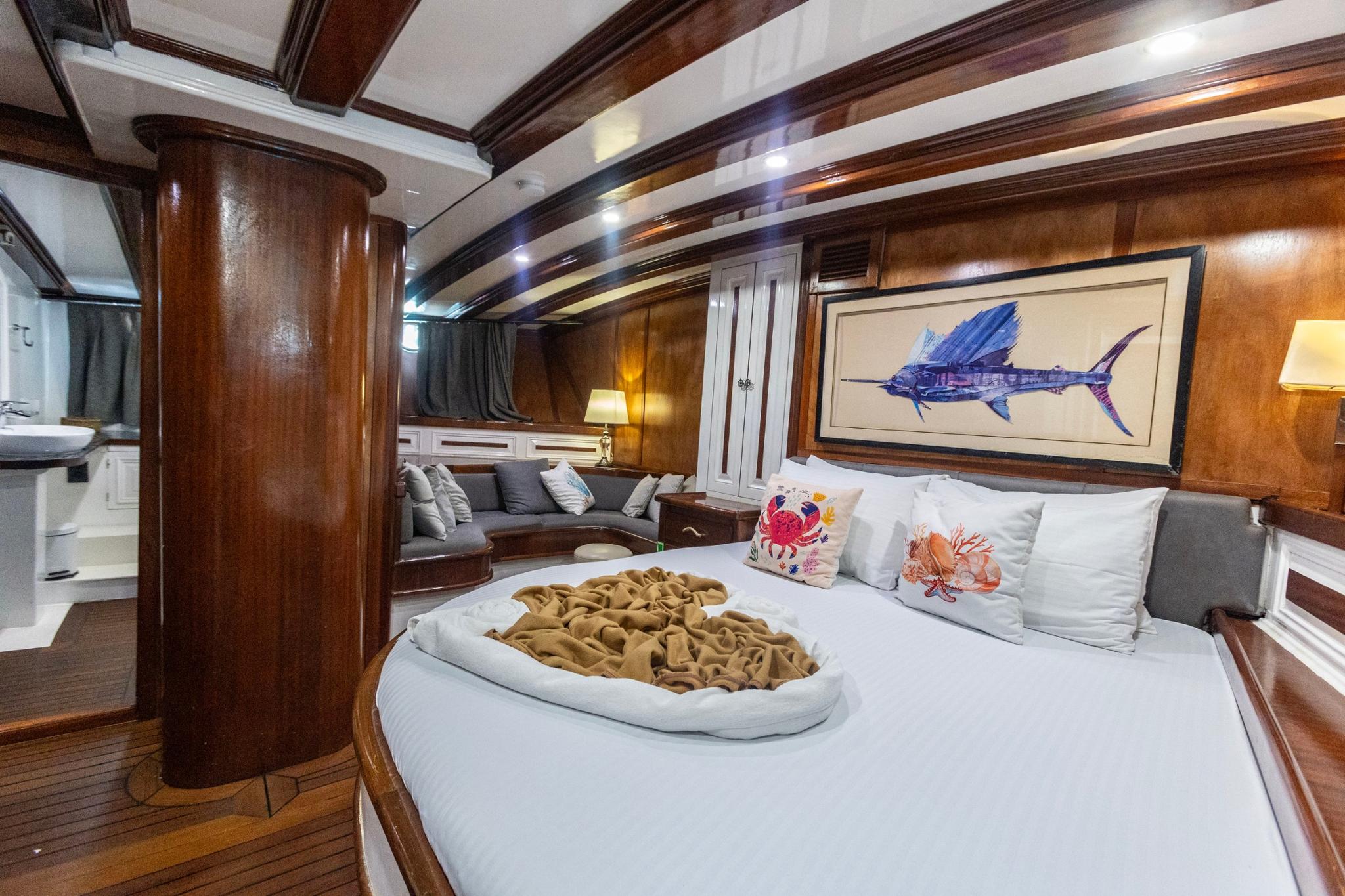yacht master cabin with king bed, decorative pillows, seating area and sailfish artwork