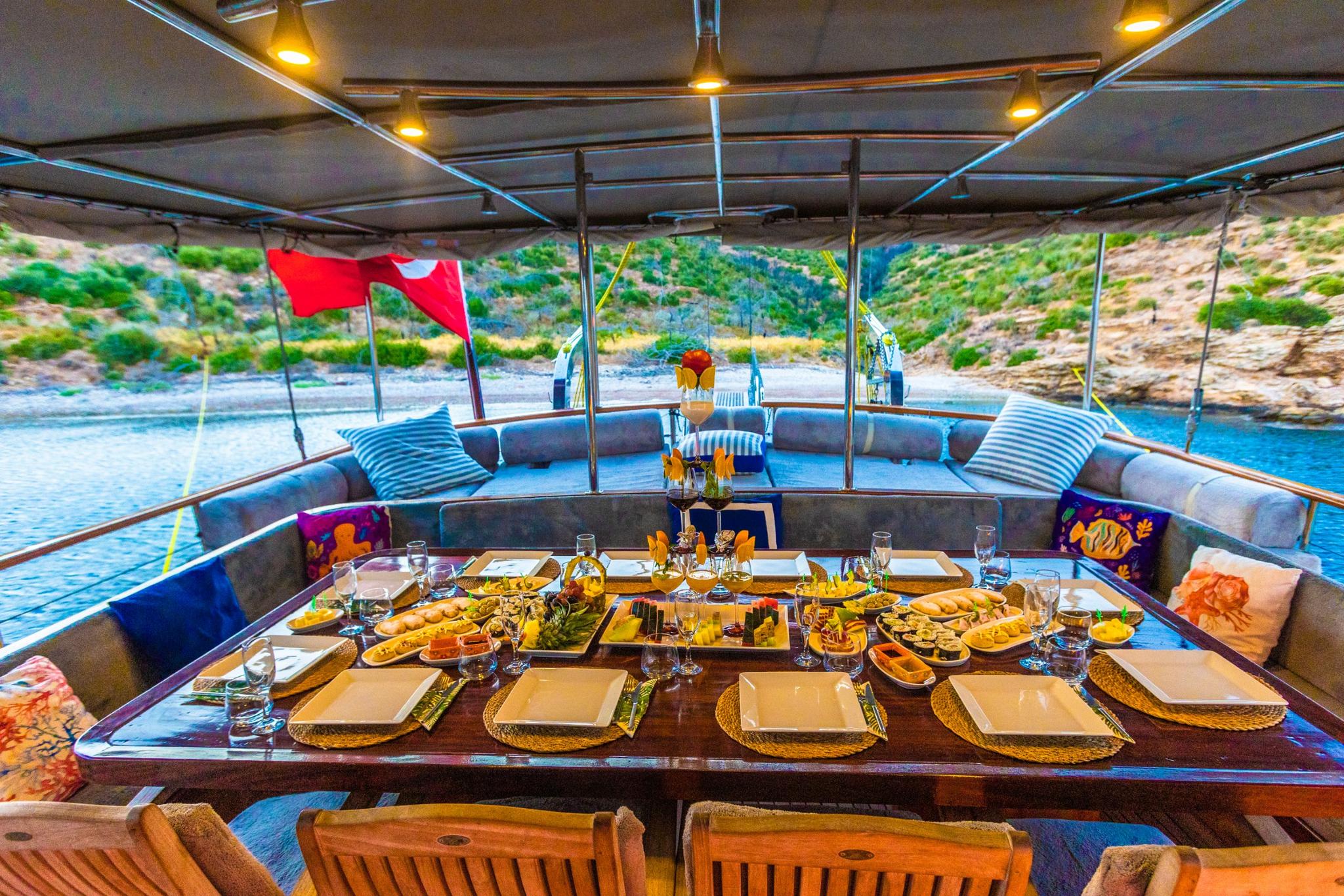 outdoor dining area with elaborate food spread, wine glasses, and Mediterranean coastline views