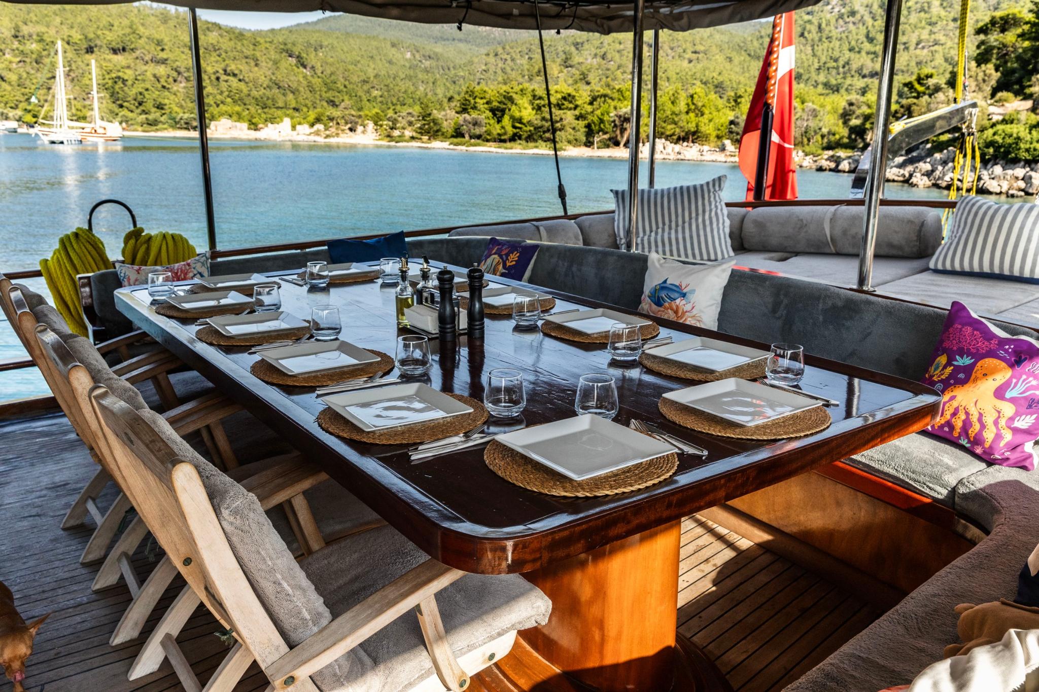 Gulet outdoor dining area with formal table setting and seating overlooking bay