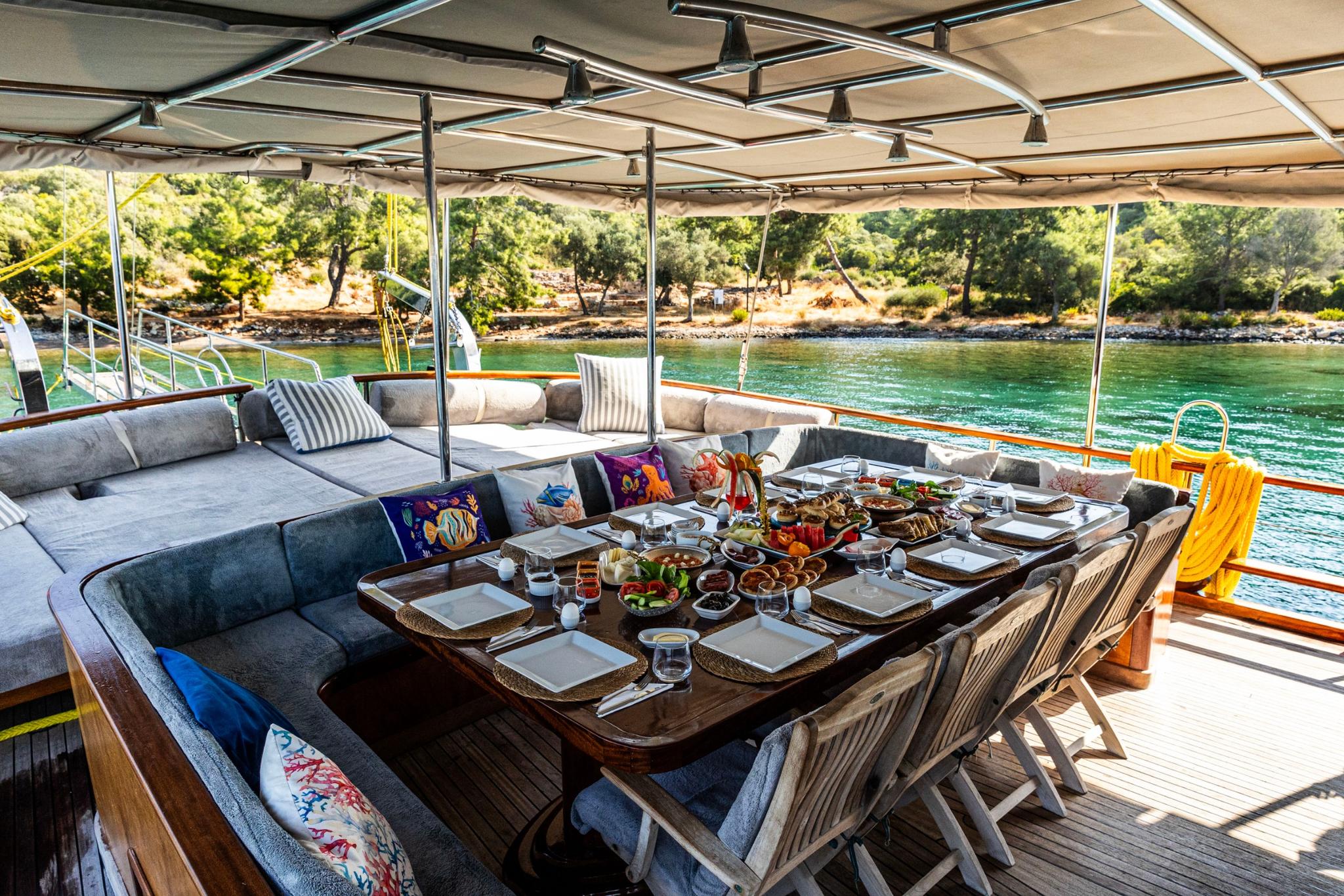 outdoor dining area with breakfast spread, cushioned seating and scenic coastal view